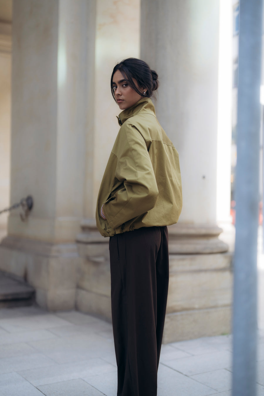 Herbst-Jacke aus Baumwolle mit Stehkragen in Khaki Oliv. Seitliche Taschen. Weite Ärmel. Braune weite Hose.