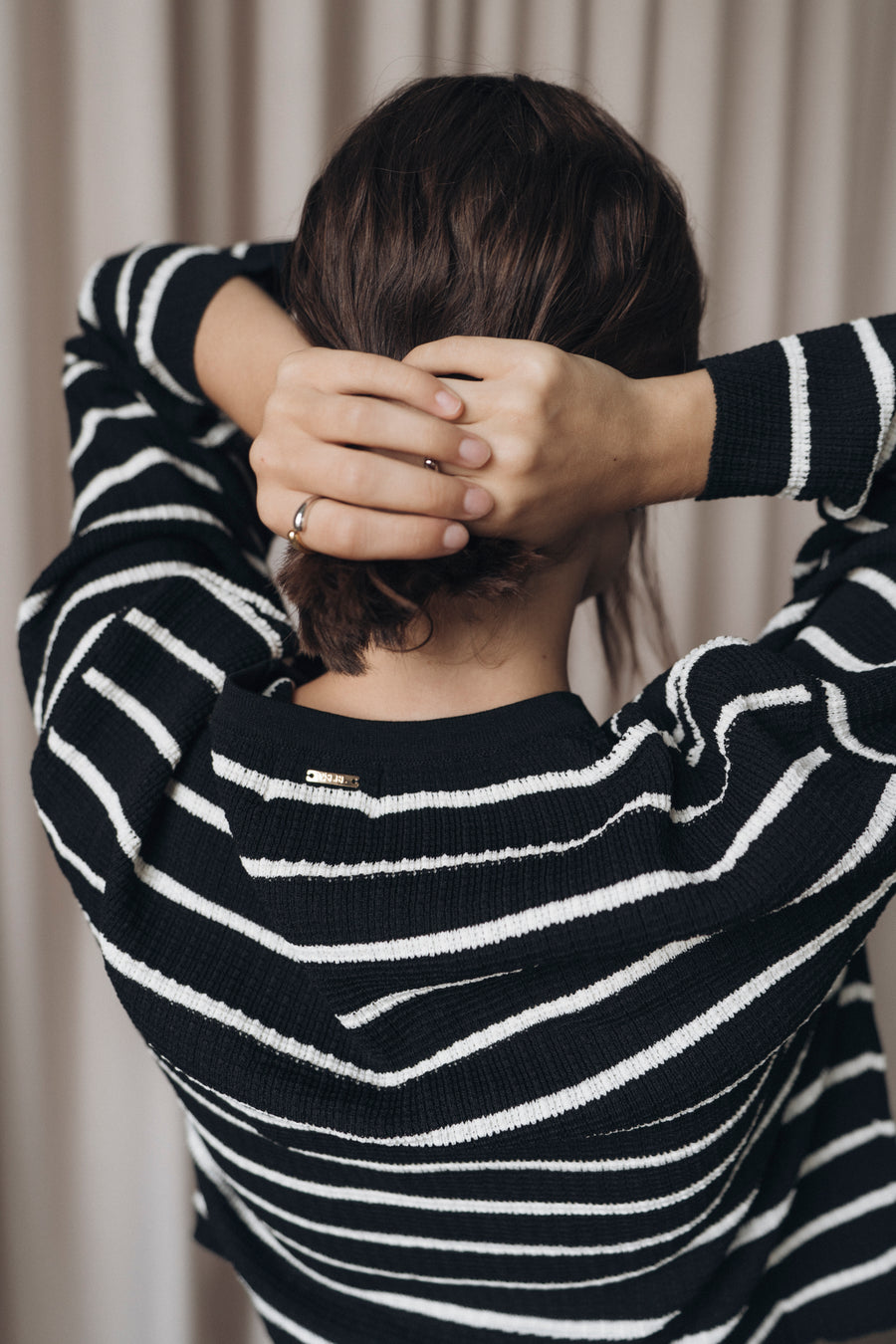 Oversized Shirt NURIA in Schwarz mit weißen Streifen – Rückansicht mit kleinem goldenen Logo-Detail.
